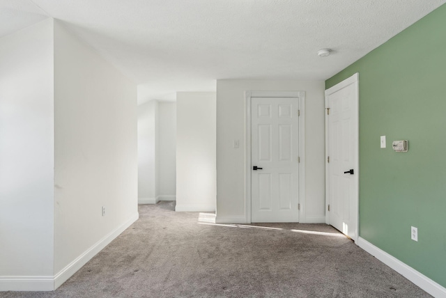 carpeted empty room featuring a textured ceiling