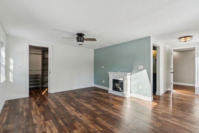 unfurnished living room featuring dark wood-type flooring and ceiling fan