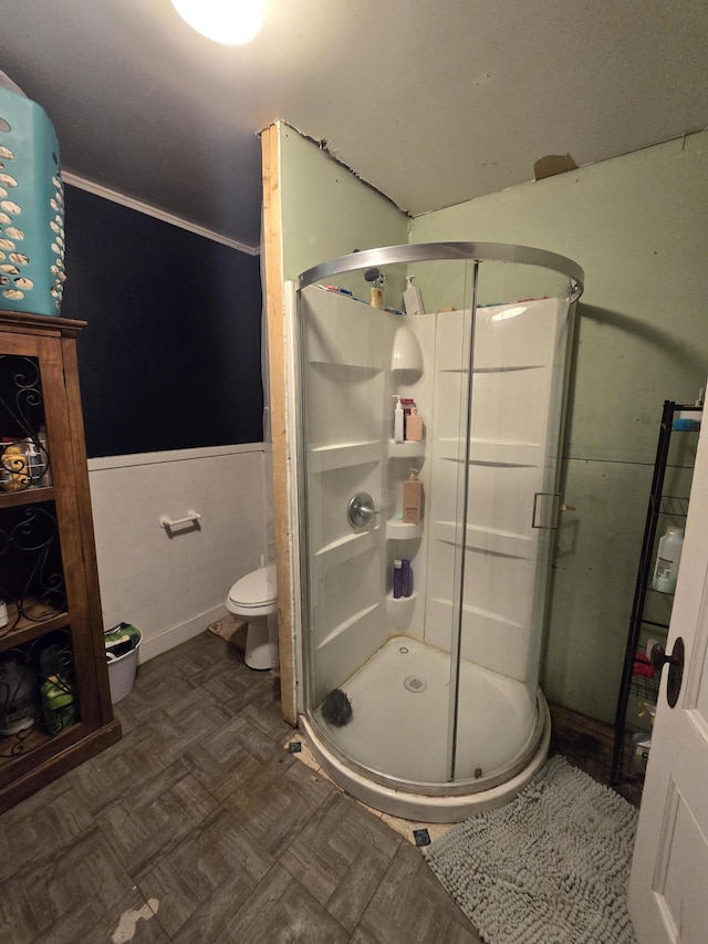 bathroom with toilet, a shower with door, tile walls, and parquet flooring