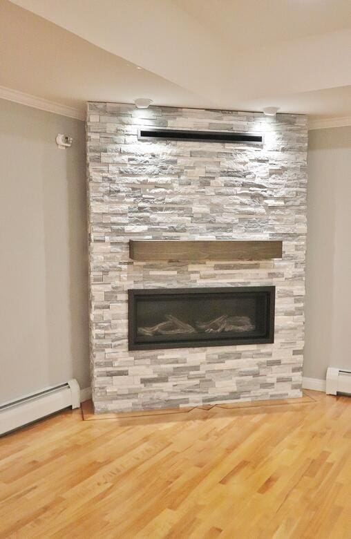 room details featuring a baseboard radiator, a fireplace, and hardwood / wood-style flooring