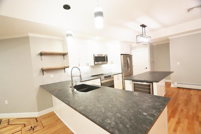 kitchen with kitchen peninsula, pendant lighting, stainless steel appliances, white cabinets, and sink