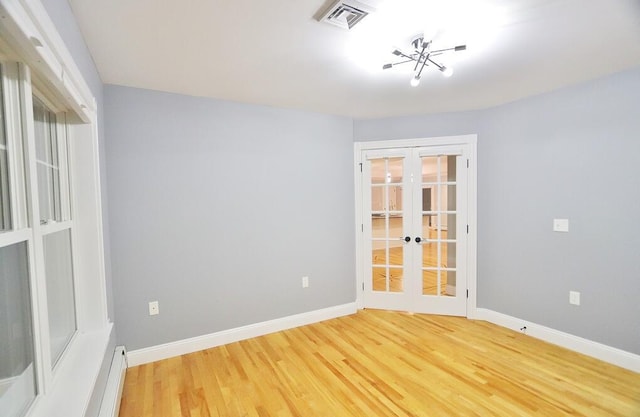 spare room with french doors, wood-type flooring, and a chandelier