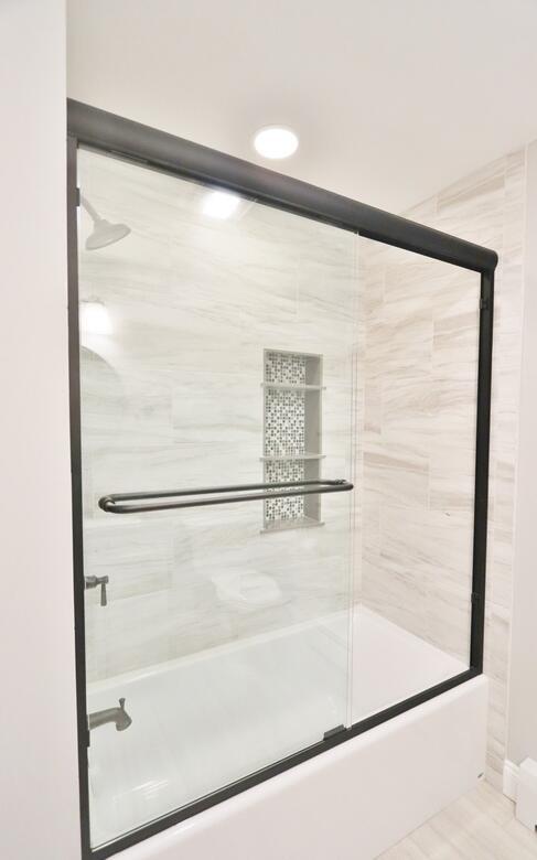 bathroom featuring tile patterned flooring and bath / shower combo with glass door