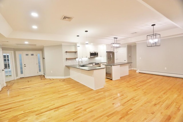 kitchen featuring stainless steel appliances, light wood-type flooring, pendant lighting, a baseboard heating unit, and white cabinetry