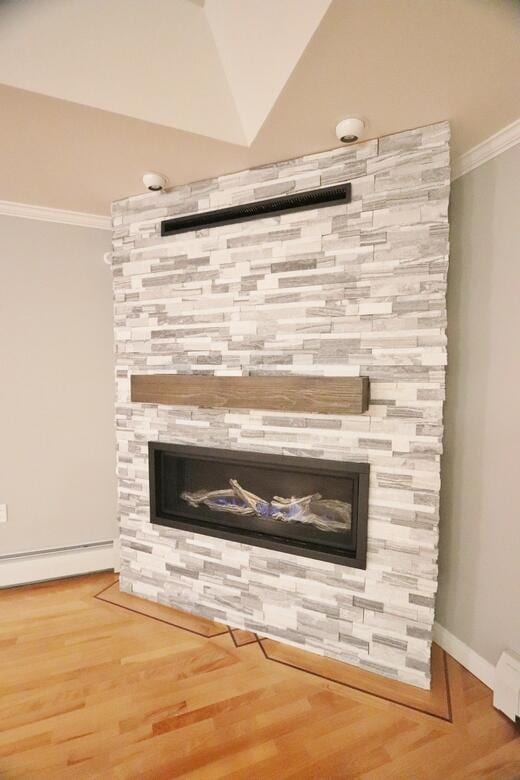 interior details with a baseboard heating unit, a fireplace, hardwood / wood-style floors, and crown molding