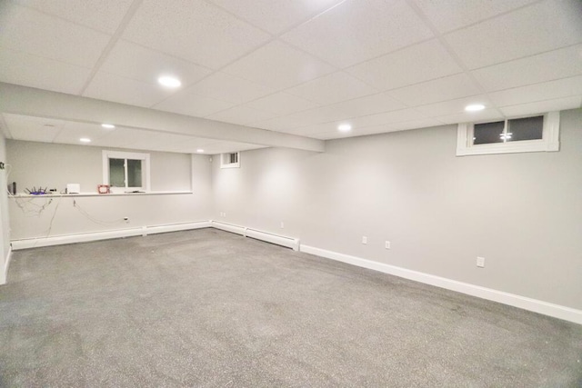 basement featuring carpet floors, a drop ceiling, and a baseboard radiator