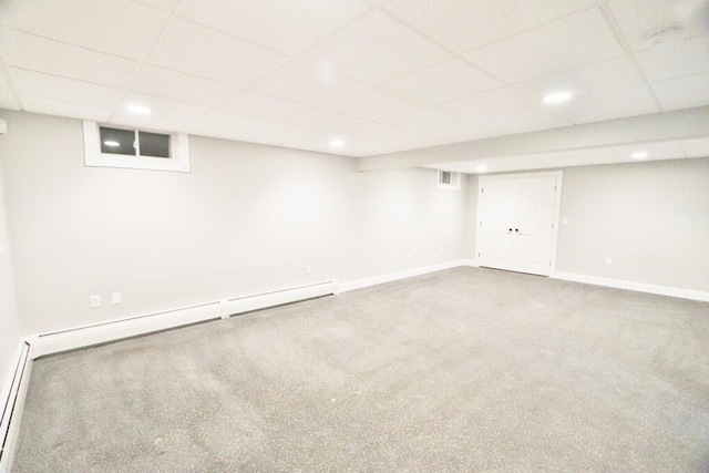 basement with a paneled ceiling, carpet, and baseboard heating