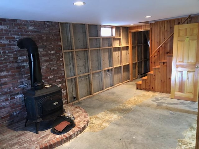 basement with a wood stove and wood walls