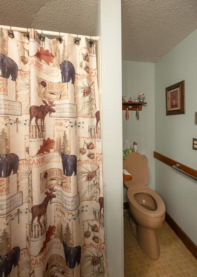 bathroom featuring curtained shower, toilet, and a textured ceiling