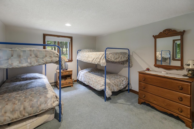 bedroom with baseboard heating, light colored carpet, and a textured ceiling