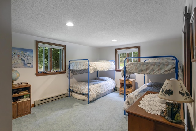 carpeted bedroom with baseboard heating, multiple windows, and a textured ceiling