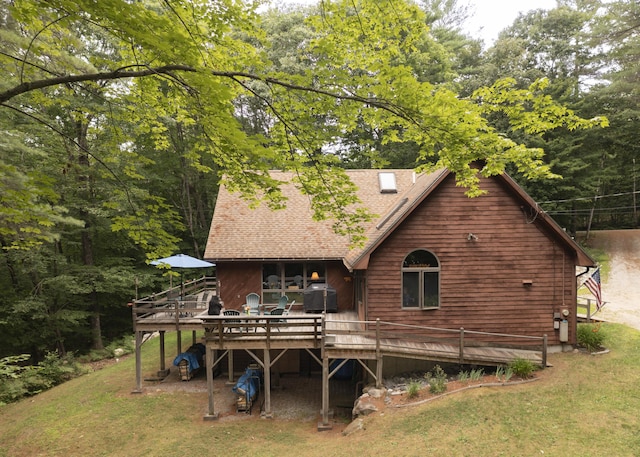 rear view of property featuring a lawn and a wooden deck