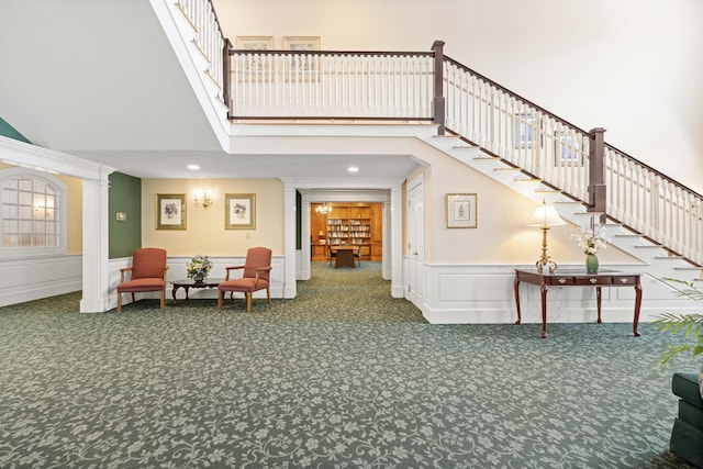 interior space with a towering ceiling, carpet flooring, and decorative columns