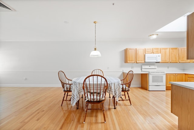 kitchen featuring light brown cabinetry, hanging light fixtures, white appliances, and light hardwood / wood-style flooring