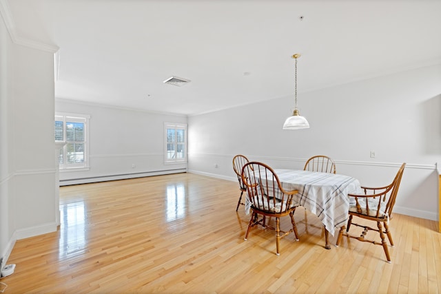 dining area featuring a baseboard radiator, ornamental molding, and light wood-type flooring