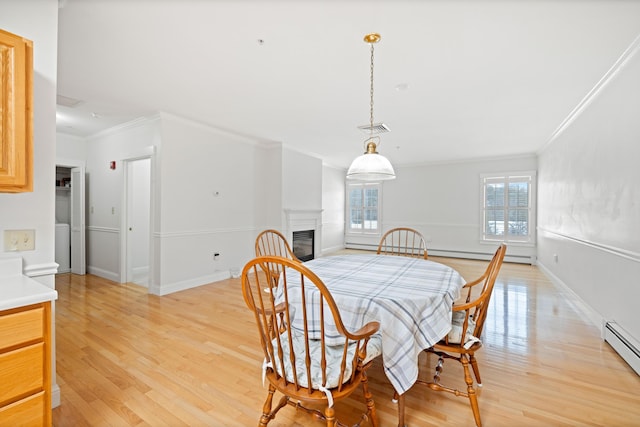 dining room with ornamental molding, light hardwood / wood-style floors, and a baseboard heating unit