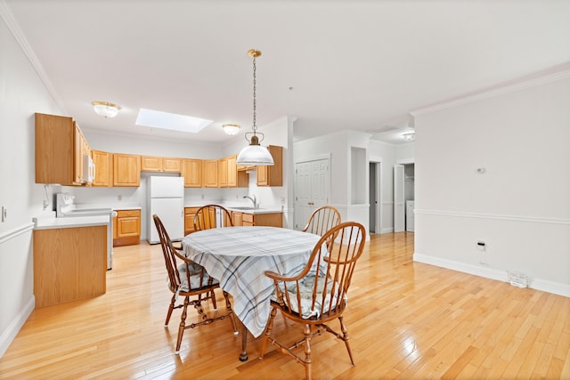 dining space with light hardwood / wood-style flooring, sink, crown molding, and a skylight