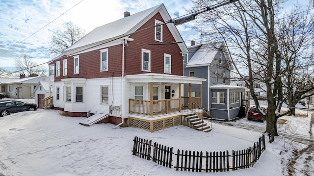 snow covered back of property featuring a porch