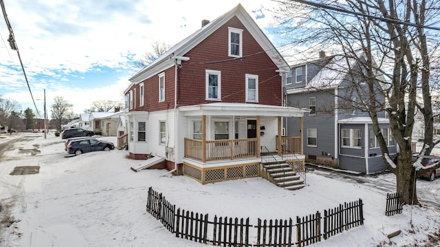 snow covered rear of property with a porch