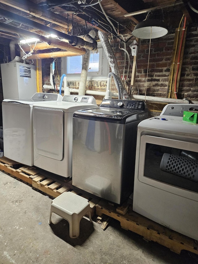 washroom featuring brick wall and separate washer and dryer