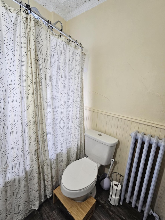 bathroom with toilet, wood-type flooring, ornamental molding, and radiator heating unit