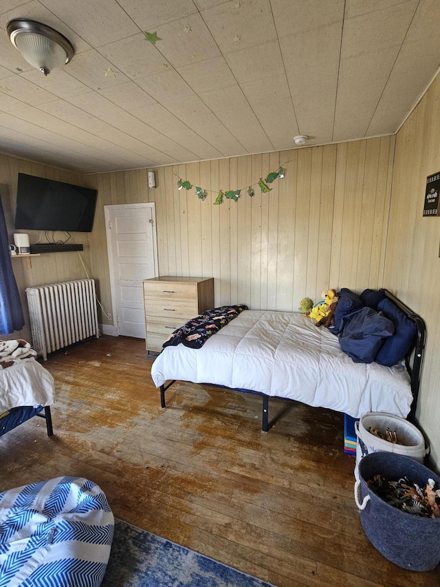 bedroom featuring wooden walls and radiator heating unit