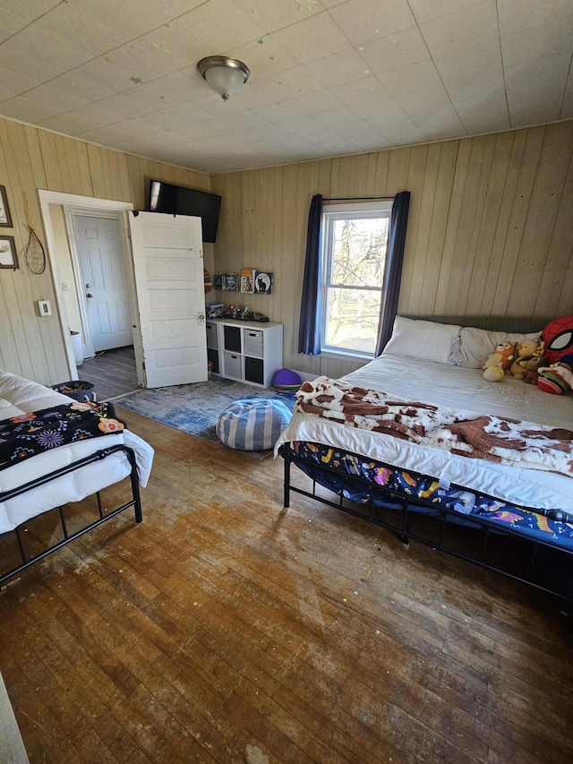 bedroom featuring dark wood-type flooring and wooden walls