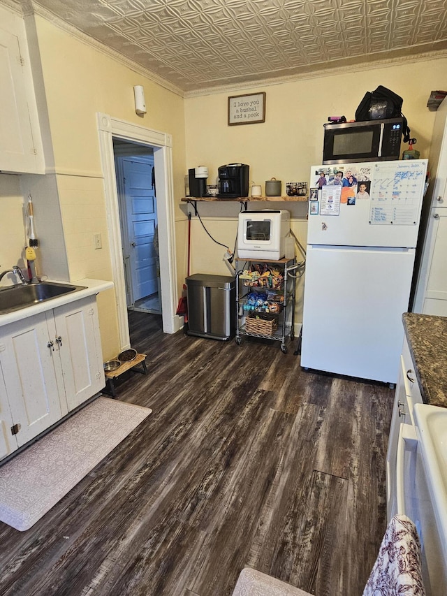 kitchen featuring white fridge, ornamental molding, dark hardwood / wood-style flooring, white cabinets, and sink