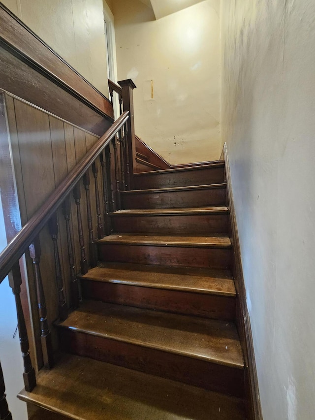 stairway featuring wooden walls