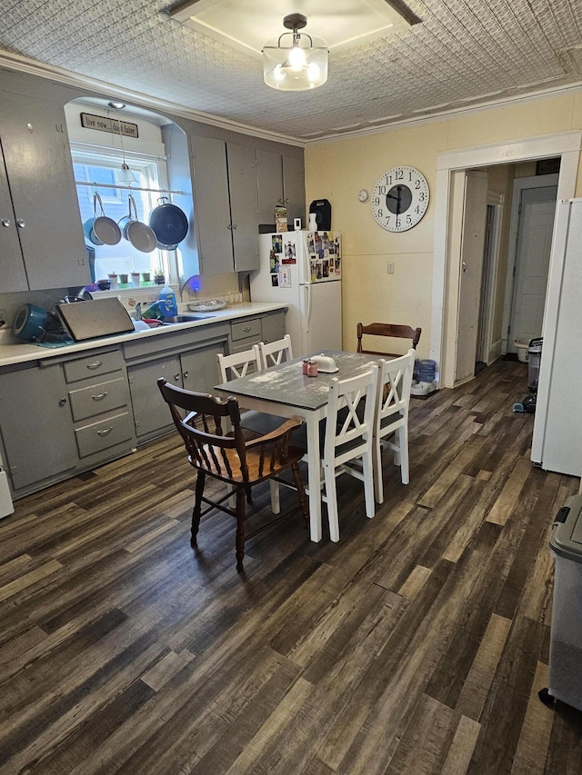 dining room featuring sink, ornamental molding, and dark hardwood / wood-style floors