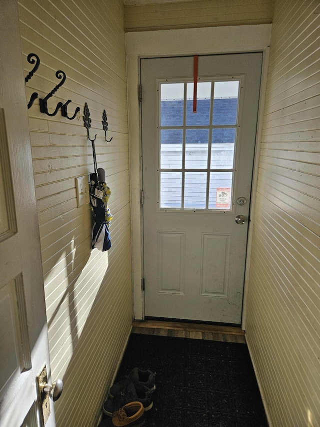 doorway with a water view and wood walls