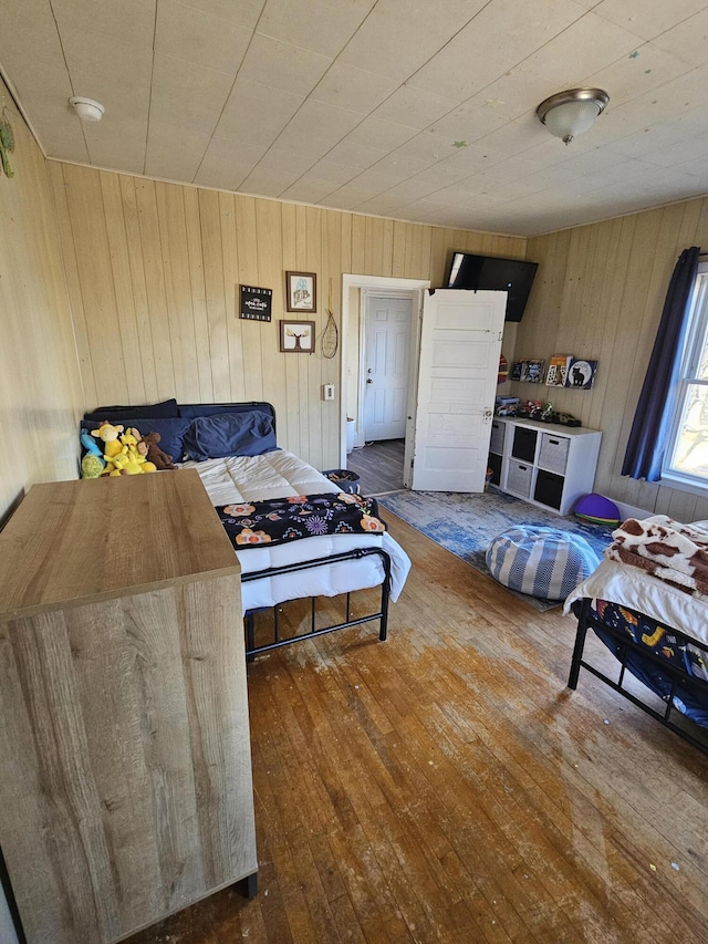 bedroom with wooden walls and dark wood-type flooring