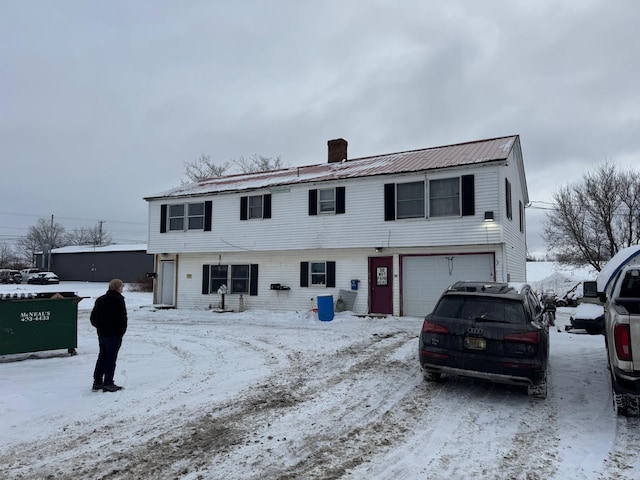10 Russ St, Caribou, ME 04736 - view of front of property featuring a chimney, dirt driveway, metal roof, and an attached garage