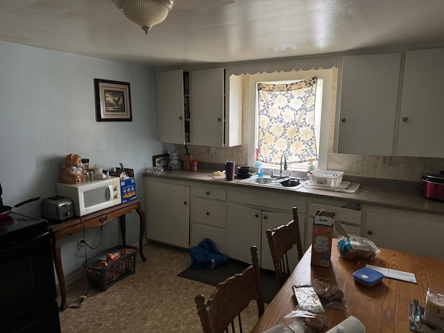10 Russ St, Caribou, ME 04736 - kitchen with white cabinetry, a sink, backsplash, and white microwave