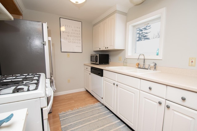 kitchen with white cabinets, white appliances, light hardwood / wood-style floors, and sink