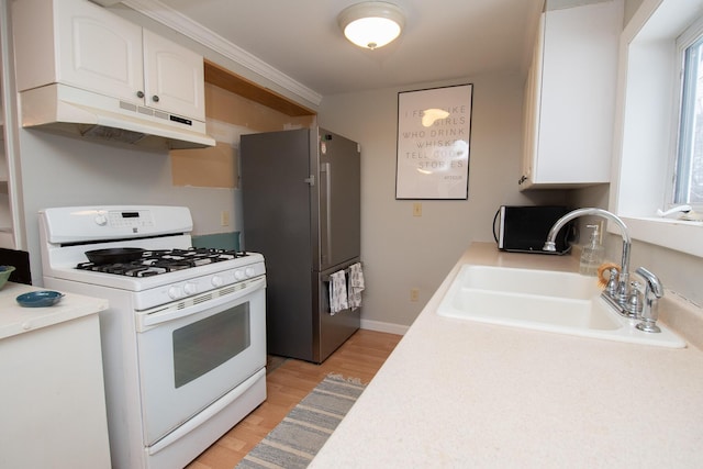 kitchen with white gas range oven, sink, white cabinets, light hardwood / wood-style floors, and stainless steel refrigerator