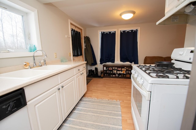 kitchen with white cabinets, light hardwood / wood-style floors, white appliances, and sink