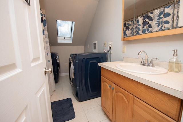 bathroom featuring tile patterned flooring, vanity, vaulted ceiling with skylight, and separate washer and dryer