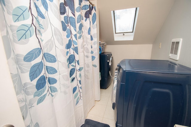 laundry room featuring light tile patterned flooring, washing machine and dryer, and a skylight