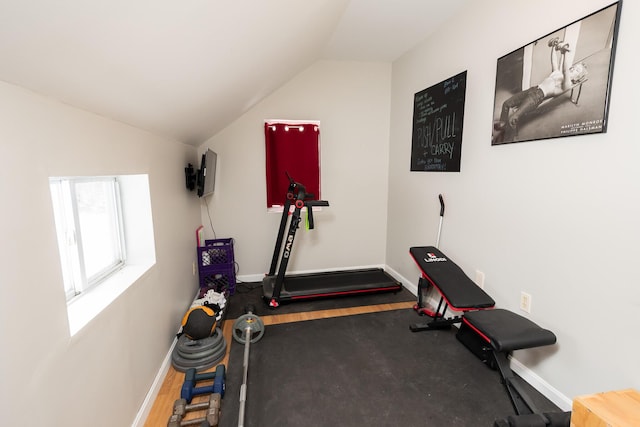 exercise room with dark wood-type flooring and vaulted ceiling