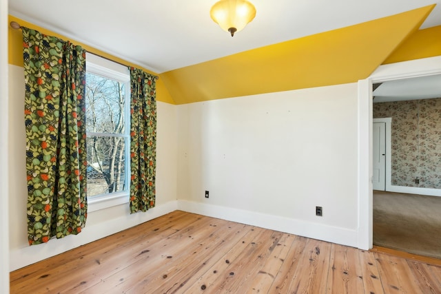 spare room with plenty of natural light, wood-type flooring, and lofted ceiling