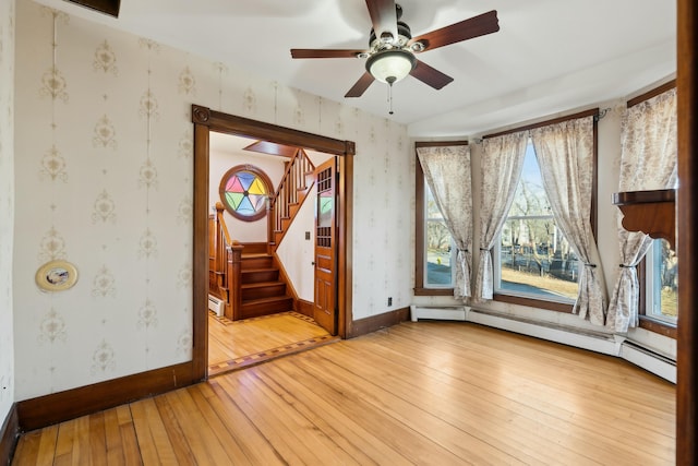 interior space featuring light wood-type flooring, ceiling fan, and a baseboard heating unit