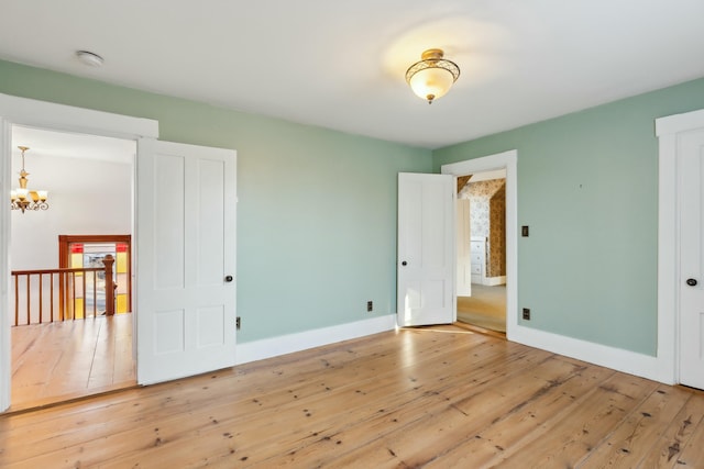 unfurnished bedroom featuring wood-type flooring and a notable chandelier