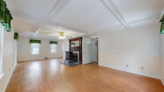 unfurnished living room with coffered ceiling, a wood stove, and beam ceiling