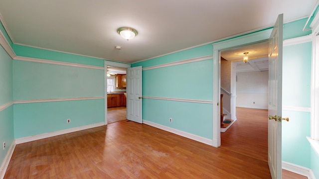 empty room with ornamental molding and light hardwood / wood-style flooring