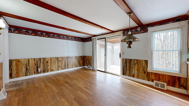 unfurnished room featuring beamed ceiling and hardwood / wood-style flooring