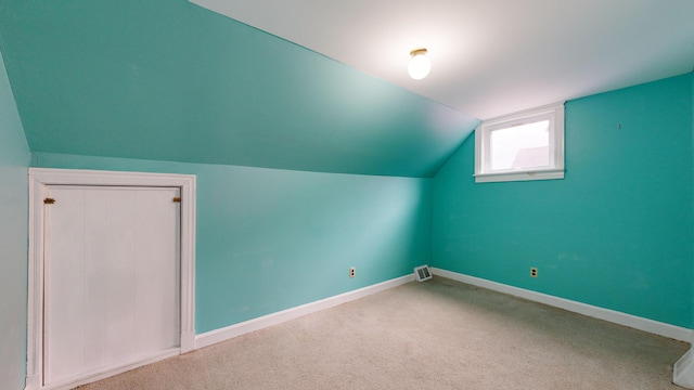 additional living space featuring vaulted ceiling and carpet flooring