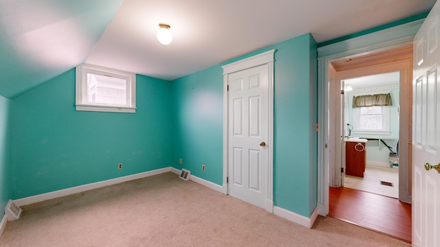 unfurnished bedroom featuring lofted ceiling and light colored carpet