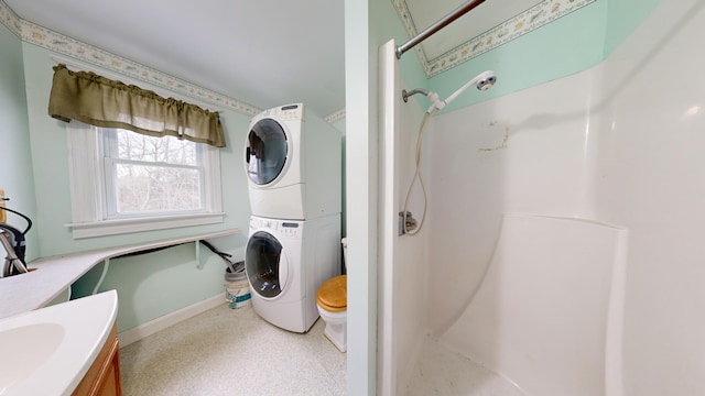 bathroom featuring vanity, stacked washer / dryer, a shower, and toilet