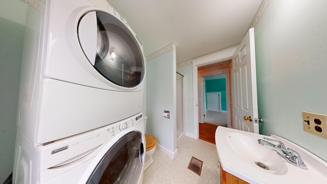 washroom featuring sink and stacked washer / dryer